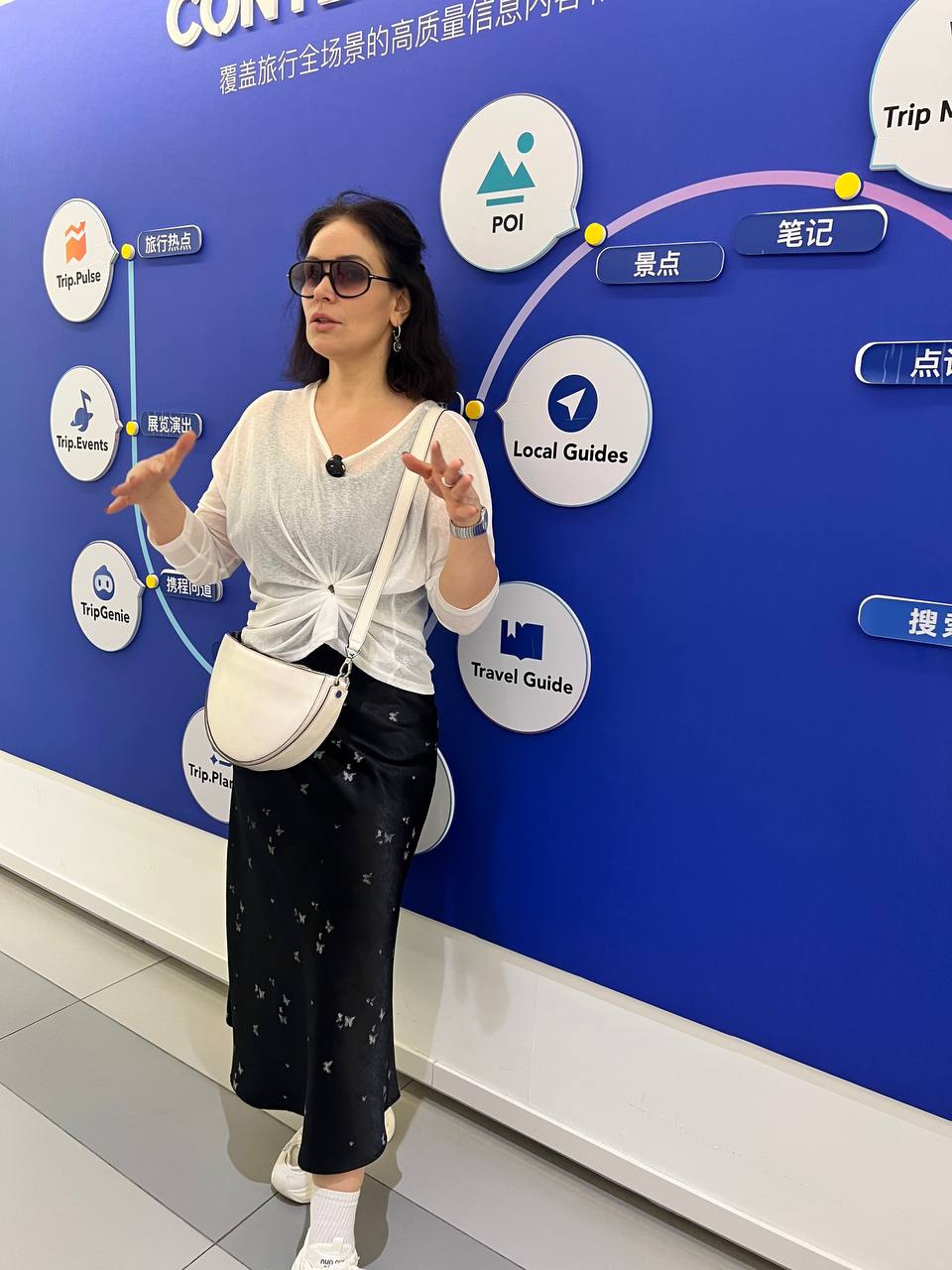 Оксана в офисе Trip.com у стены с travel-сервисами